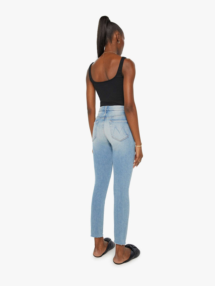 Back view of a womens light blue jean featuring a high rise a skinny fit, and a raw ankle fray.