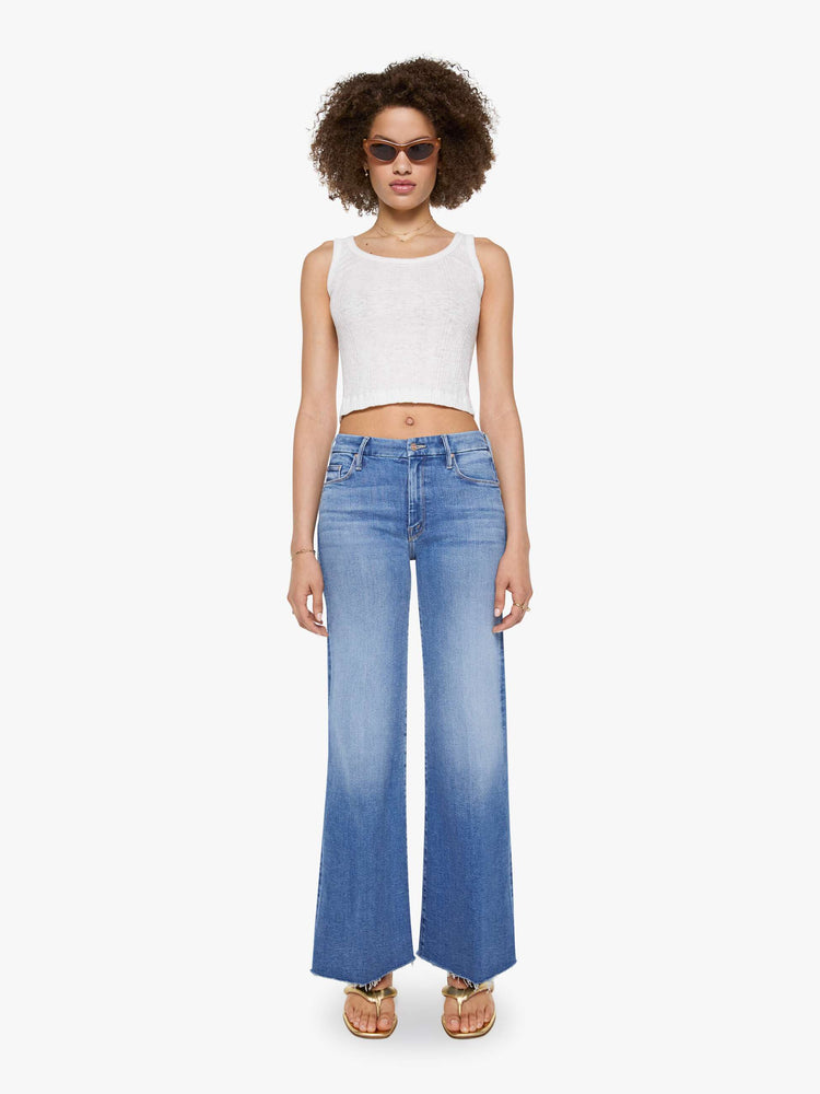 Front view of a woman in a mid blue high waisted wide leg jean with a 31-inch inseam and a frayed hem.
