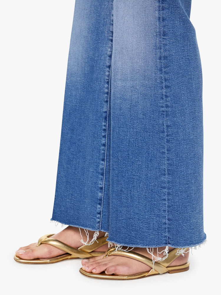 Hem view of a woman in a mid blue high waisted wide leg jean with a 31-inch inseam and a frayed hem.