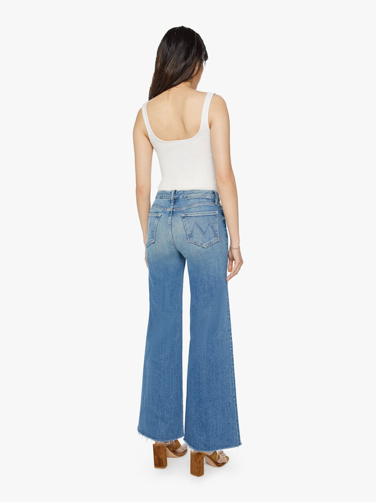 Back view of womens high waisted medium blue wash wide leg jean with a frayed hem and fading.