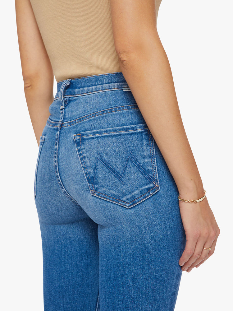 Close up back view of a woman high-rise skinny jean has a zip fly, ankle-length inseam and a frayed step-hem in a mid-blue wash.