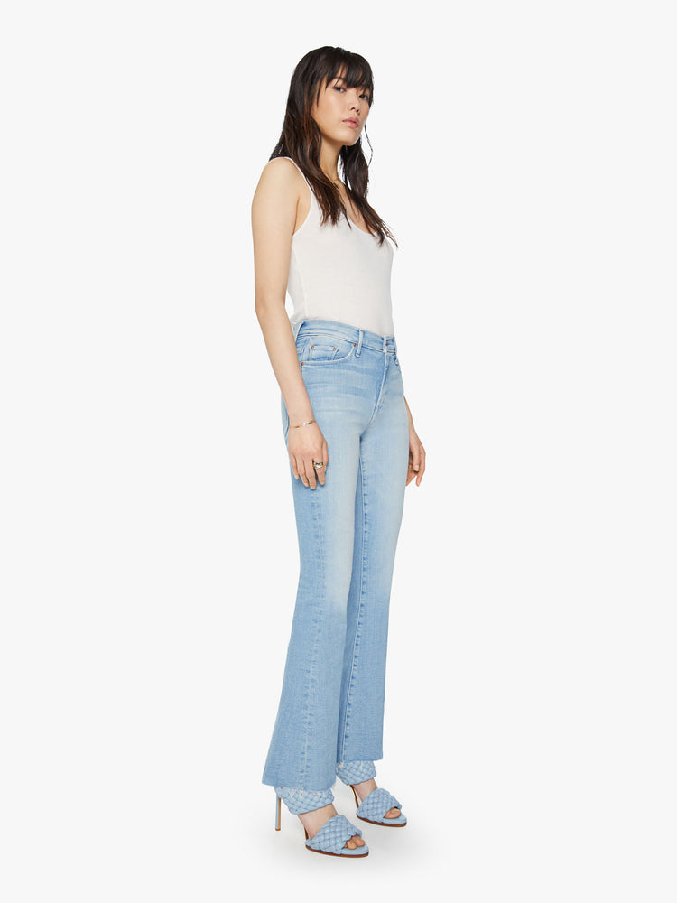 Side angle view of a womens mid rise flare light blue wash jean with a fading and whiskering.
