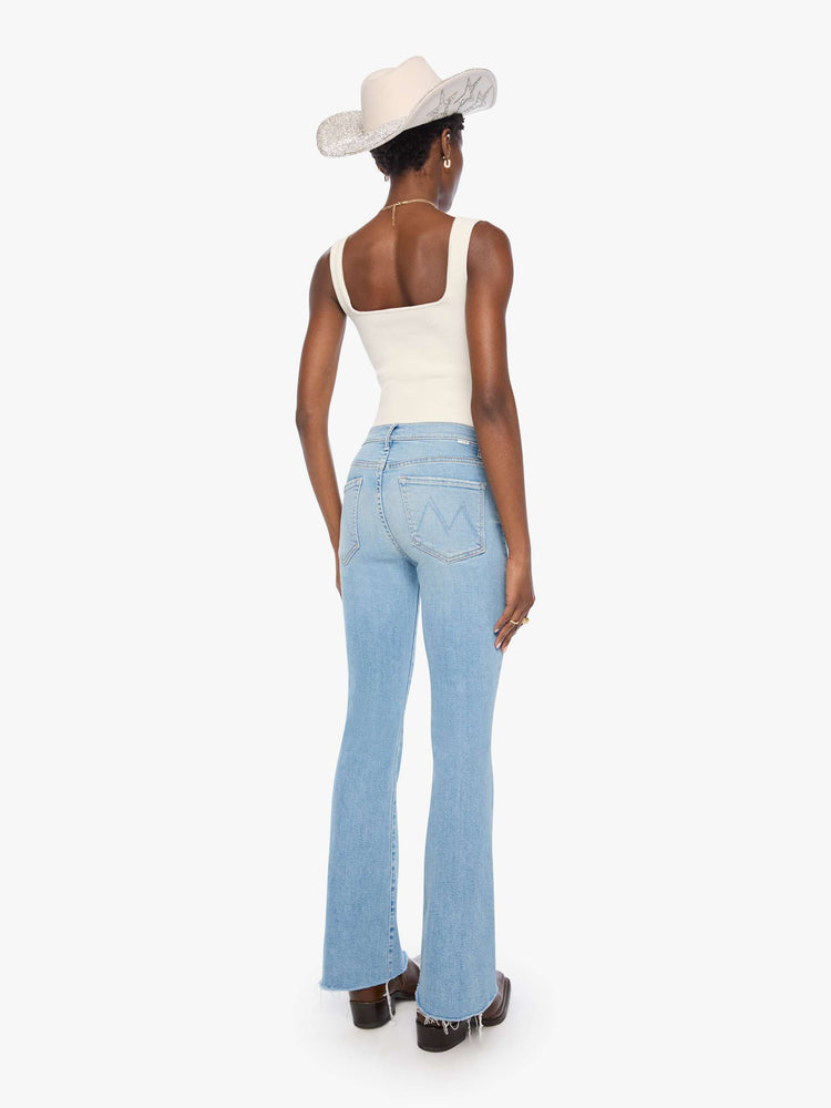 Back view of a woman in a light blue mid-rise flare has a zip fly, 31-inch inseam and a frayed hem.