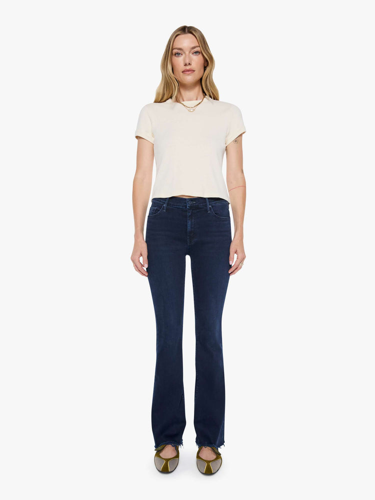 Front view of a woman in a dark blue wash mid-rise flare with a 31-inch inseam and frayed hem.
