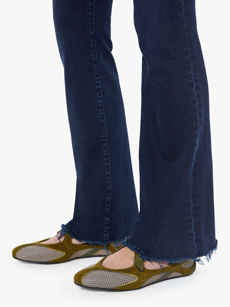 Hem view of a woman in a dark blue wash mid-rise flare with a 31-inch inseam and frayed hem.