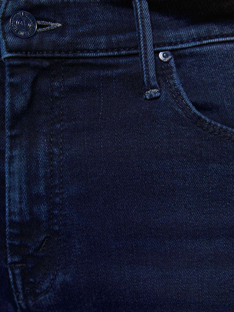 Close up view of a woman in a dark blue wash mid-rise flare with a 31-inch inseam and frayed hem.