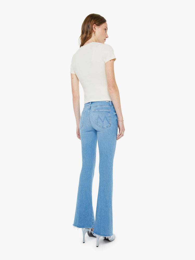 Back view of a woman in a light blue mid-rise flare has a zip fly, 31-inch inseam and a frayed hem.