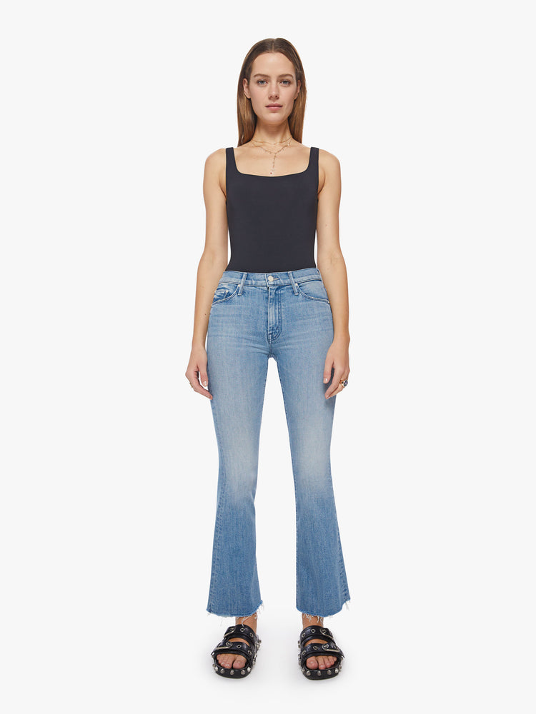 Front view of a woman flare jean has a mid rise with a 31-inch length inseam and a frayed hem in a light blue wash.