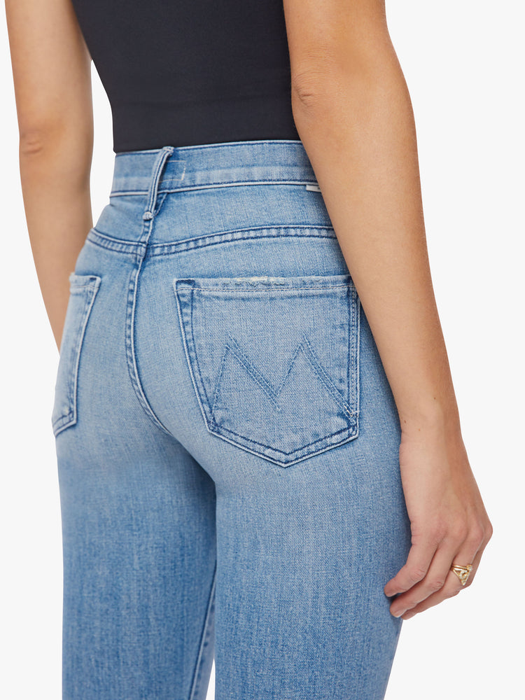Back close up view of a woman flare jean has a mid rise with a 31-inch length inseam and a frayed hem in a light blue wash.