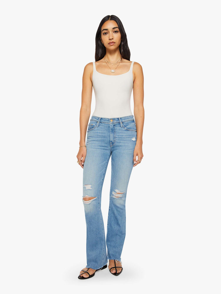 Front view of a woman in a vintage blue mid-rise flare has a zip fly, 31-inch inseam and a frayed hem.