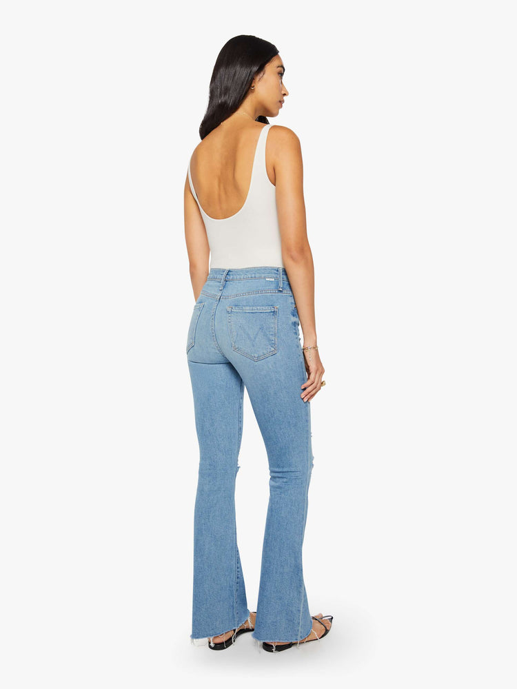 Back view of a woman in a vintage blue mid-rise flare has a zip fly, 31-inch inseam and a frayed hem.