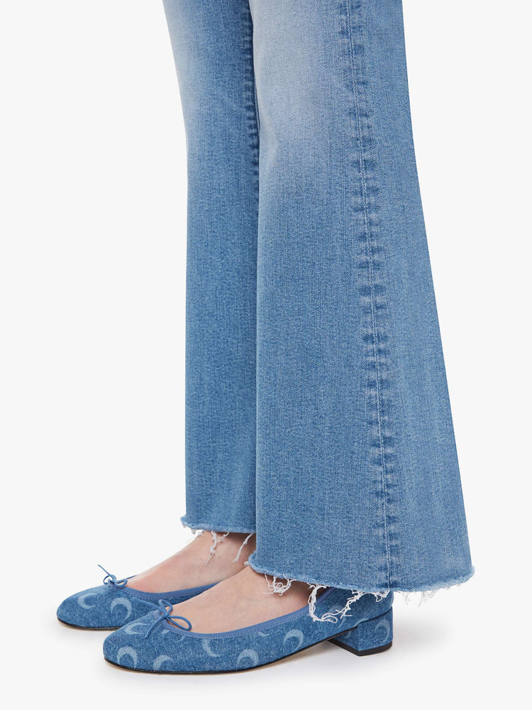 Hem view of a woman in a light blue  mid-rise flare has a zip fly, 32.25-inch inseam and a frayed hem. 