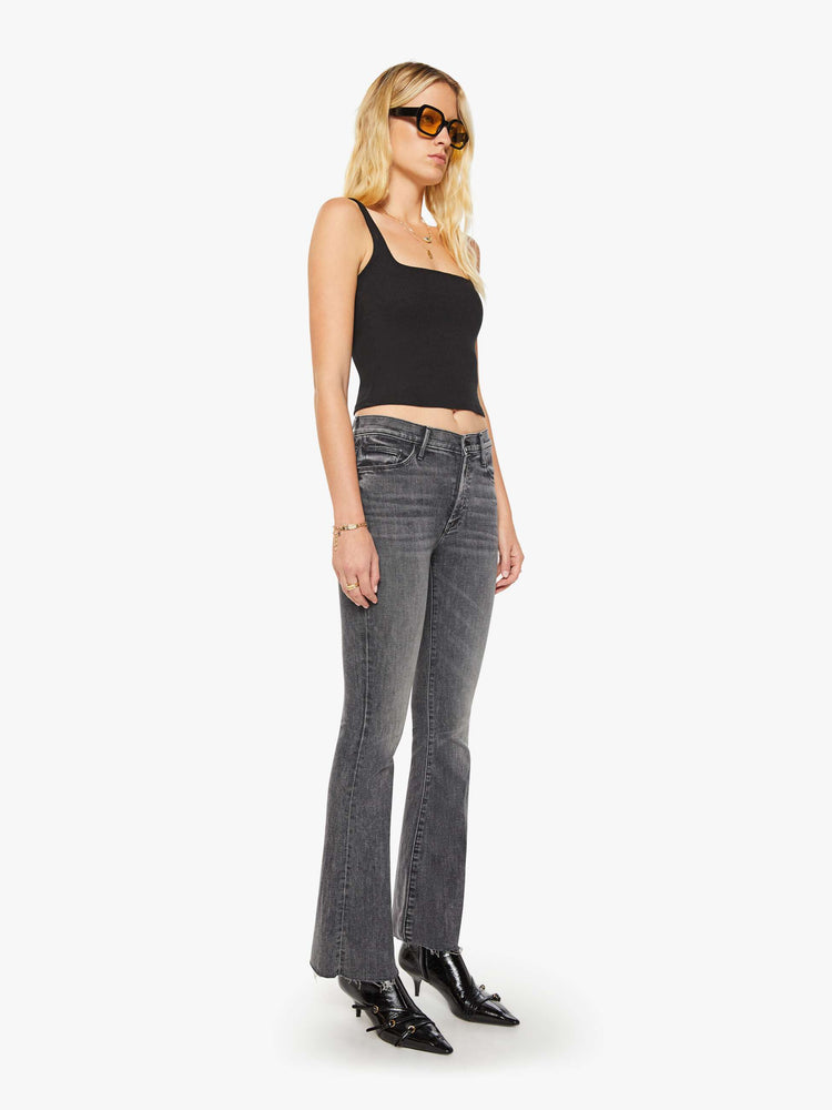3/4 view of women's gray mid rise flare jean with zip fly and frayed hems.