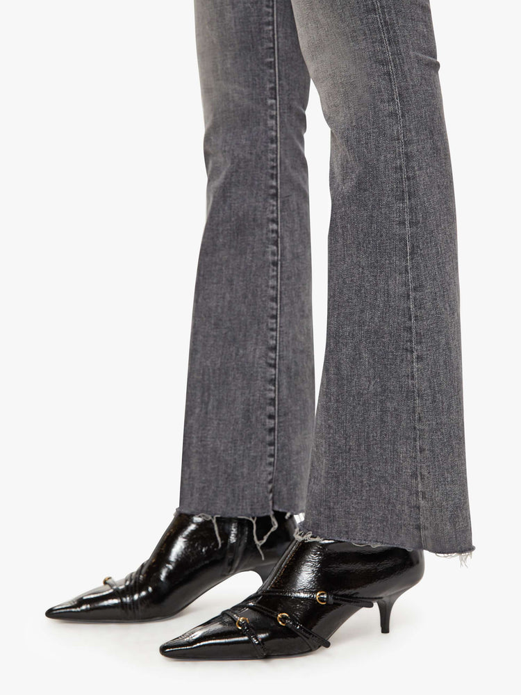 Hem view of women's gray mid rise flare jean with zip fly and frayed hems.