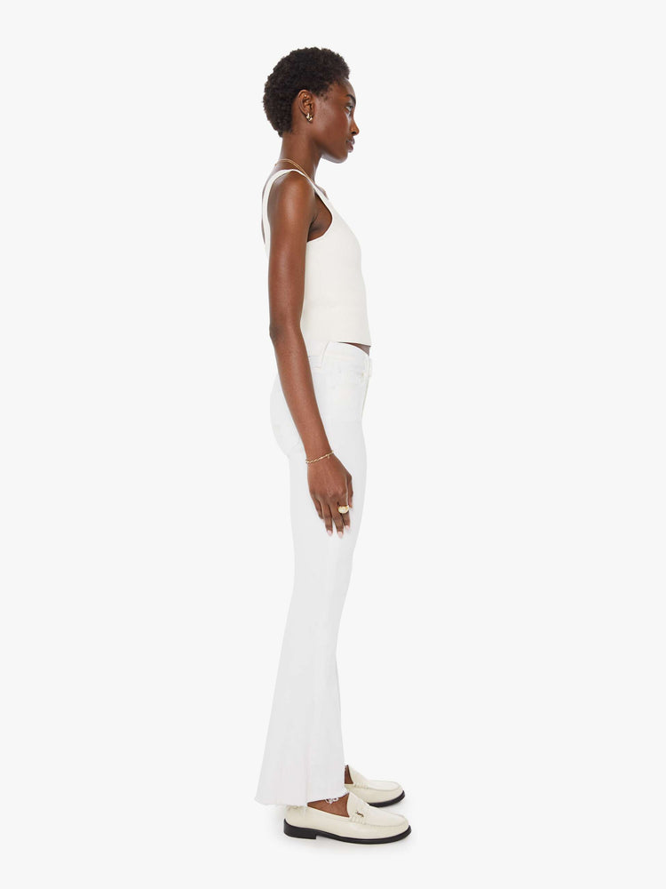 Side view of a womens white wash jean featuring a mid rise, flare leg, and a frayed hem.