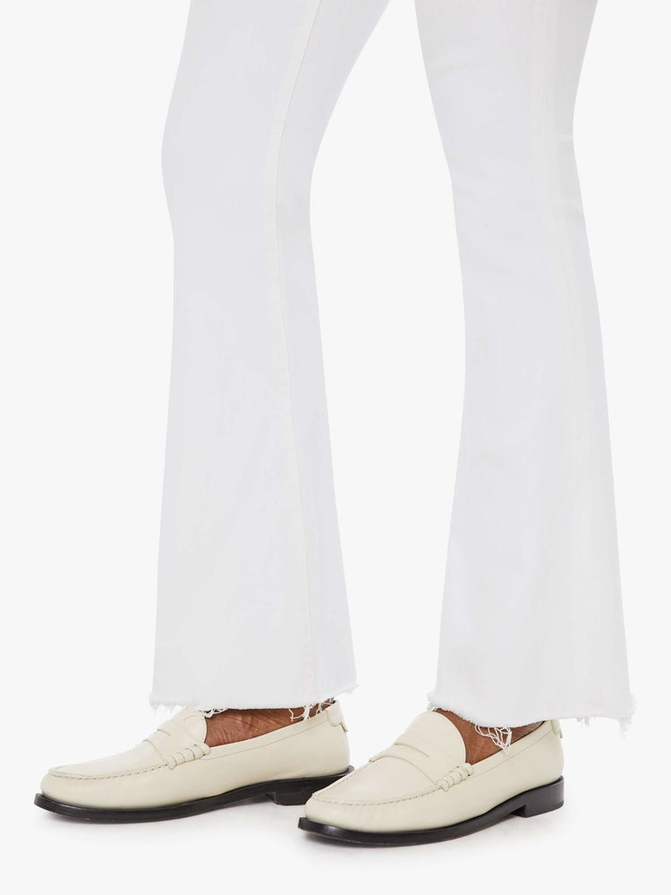 Hem view of a womens white wash jean featuring a mid rise, flare leg, and a frayed hem.