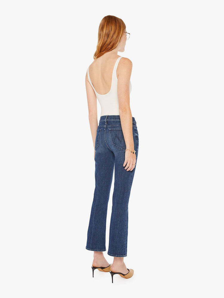 Back view of a womens dark denim wash jean featuring a mid rise and a ankle length flare.