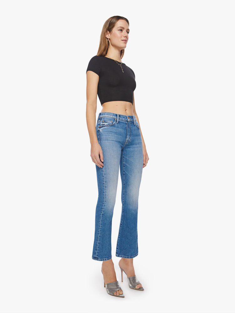 Side angle view of a woman light blue wash, narrow flare jeans with a high rise and an ankle-length inseam with a clean hem.