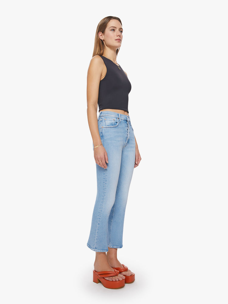 Side angle view of a woman high-rise flare with a button fly and a clean ankle-length hem in a light blue wash.