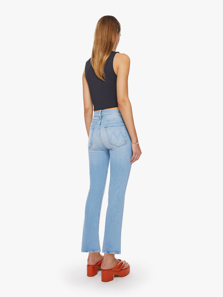 Back view of a woman high-rise flare with a button fly and a clean ankle-length hem in a light blue wash.