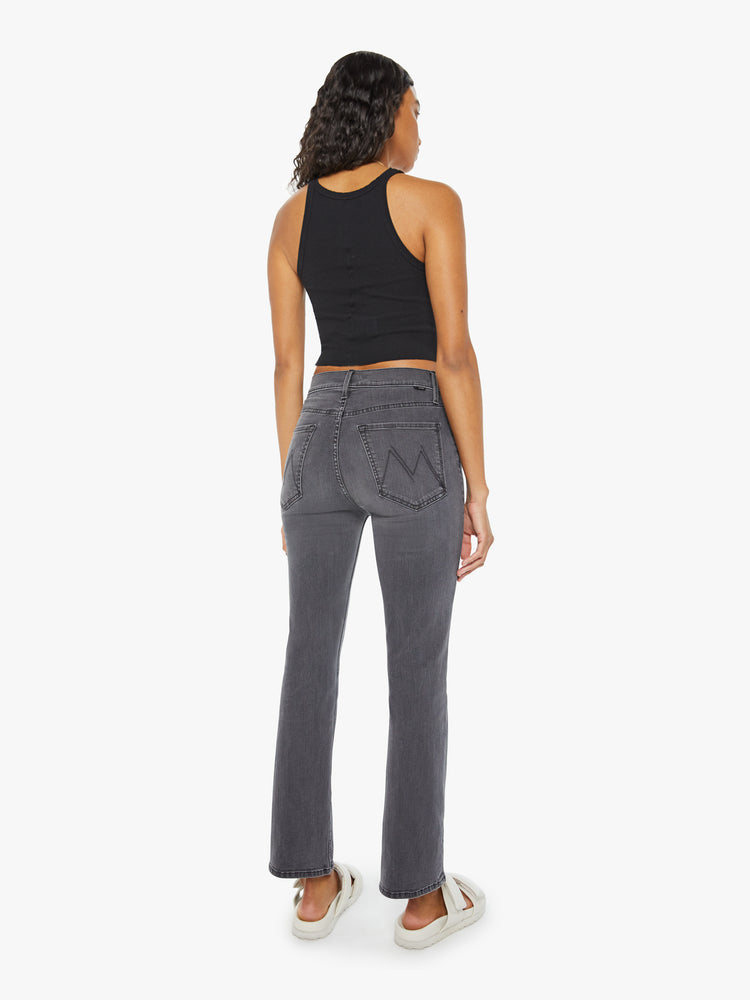 Back view of a woman in high-rise flare with a button fly and a clean ankle-length hem dark grey wash.