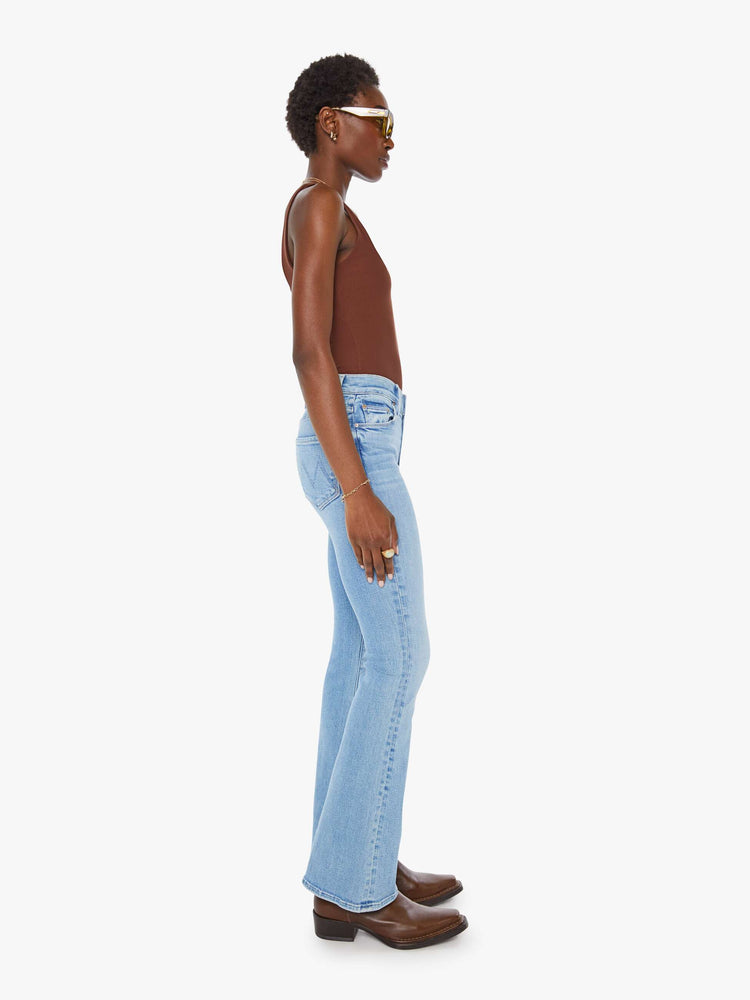 Side view of a woman in a mid rise with a 31-inch inseam and a clean hem in a mid blue wash.