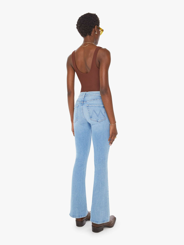 Back view of a woman in a mid rise with a 31-inch inseam and a clean hem in a mid blue wash.