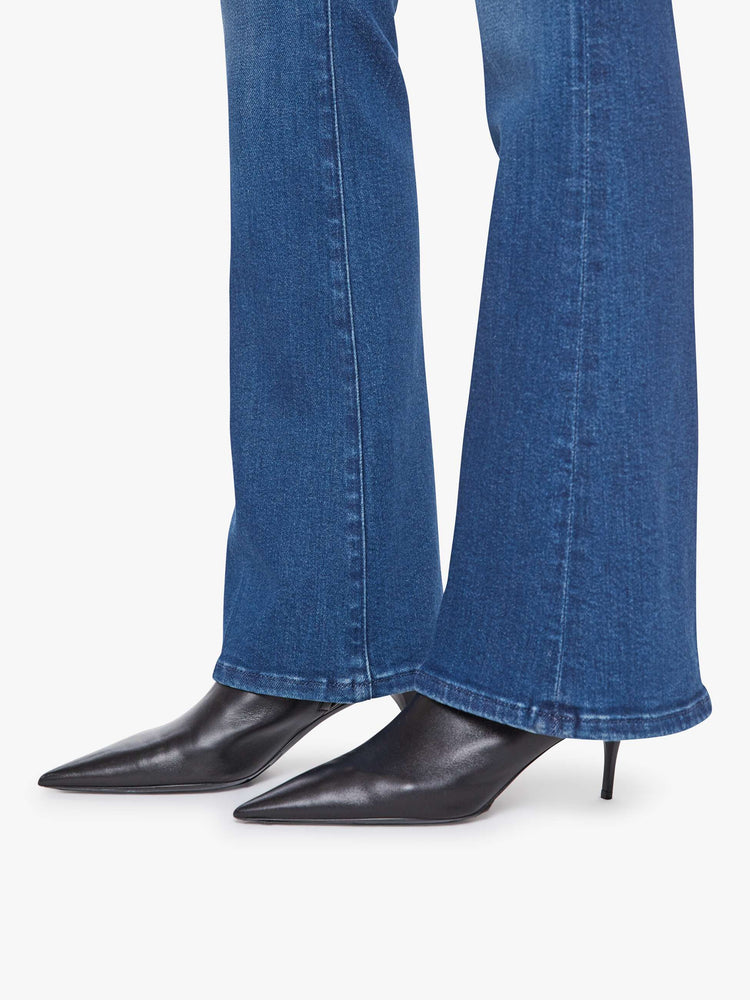 Hem view of a woman in a med blue flare jean with a mid rise, zip fly, 31-inch inseam and a clean hem.