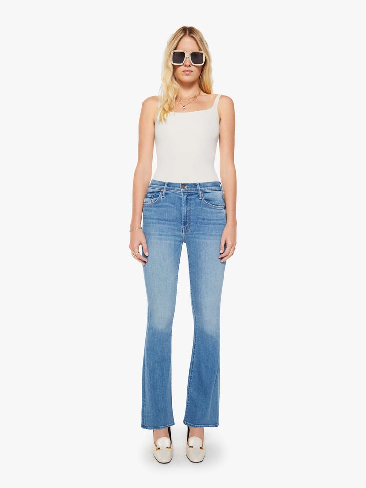 Front view of a woman in a blue flare mid rise with a 32.5-inch inseam and a clean hem.