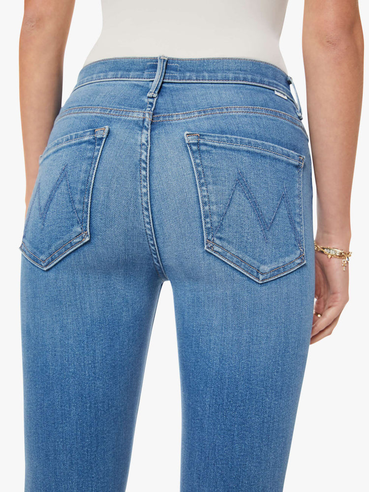 Close up view of a woman in a blue flare mid rise with a 32.5-inch inseam and a clean hem.