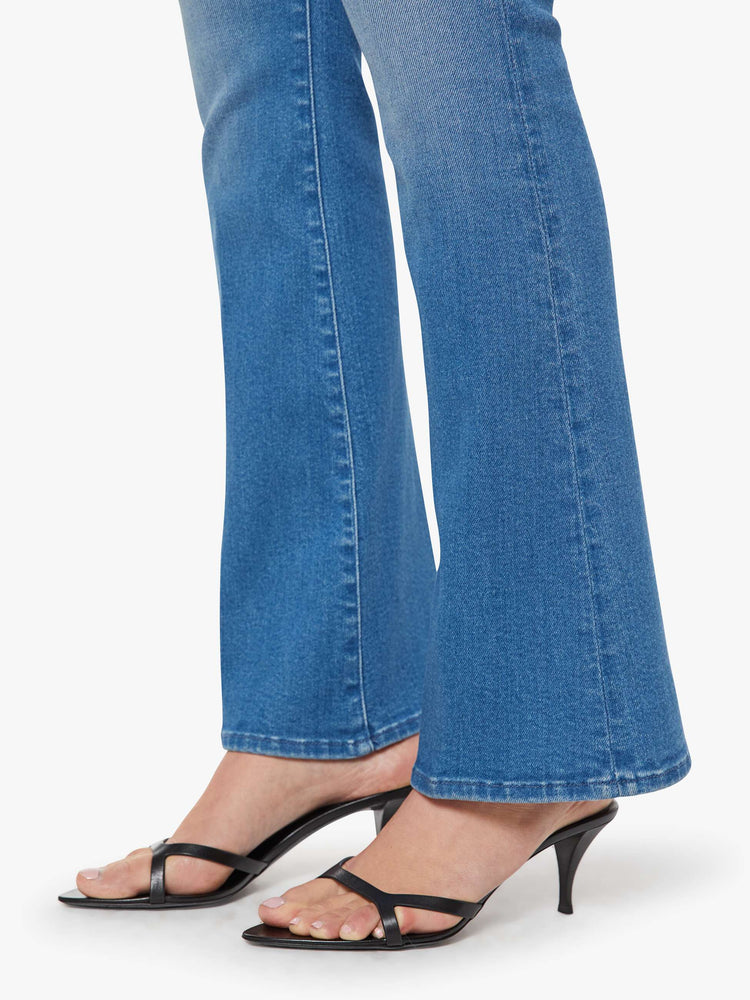 Hem view of a woman in a med blue flare jean has a mid rise with a 31-inch inseam and a clean hem.