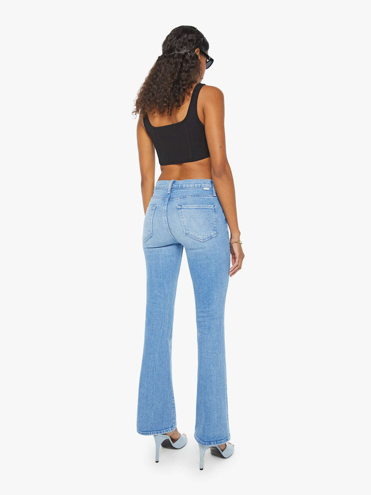 Back view of a woman in a mid rise light blue flare jean with a clean hem.