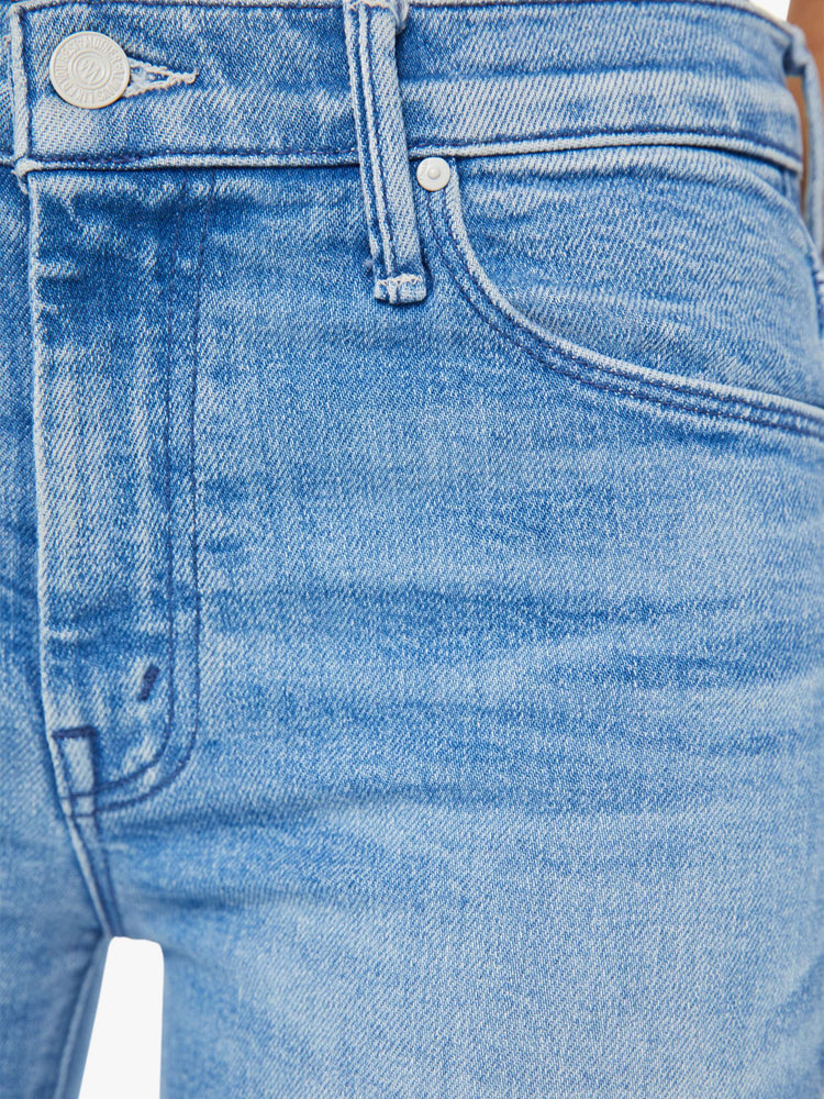 Detailed view of a woman in a mid rise light blue flare jean with a clean hem.
