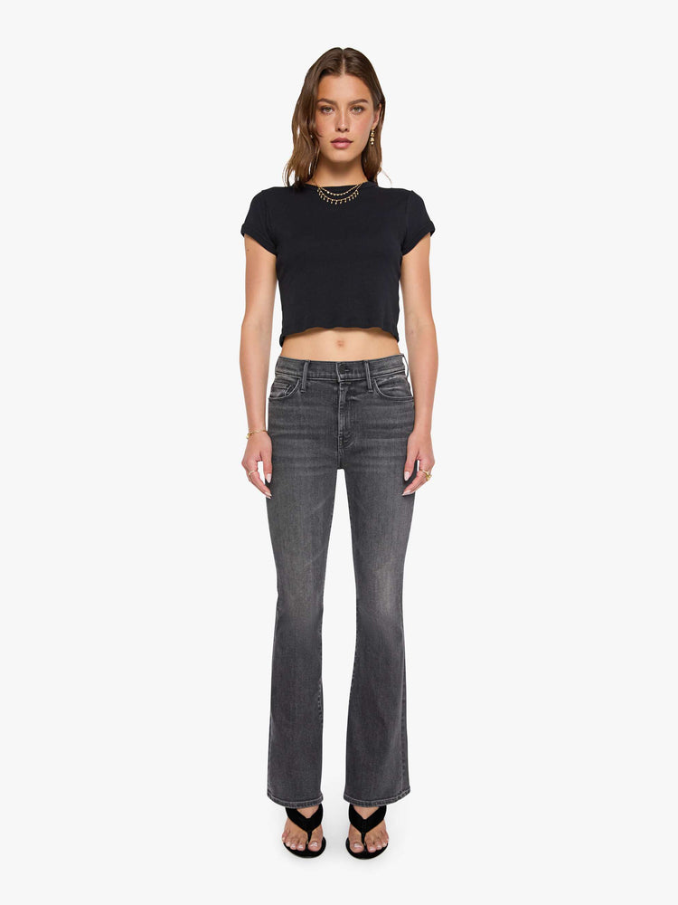 Front view of a woman in a faded black flare jean with a mid rise and 31-inch inseam and a clean hem. 