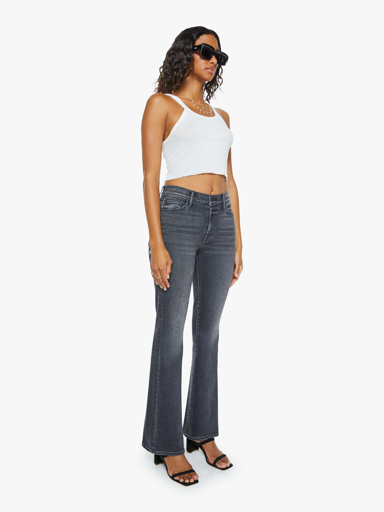 Front view of a woman in a faded black flare jean with a mid rise and 31-inch inseam and a clean hem. 