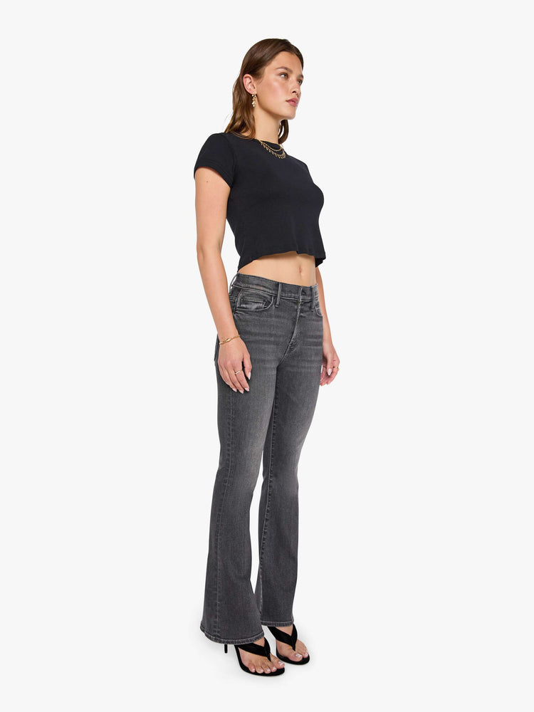 Front view of a woman in a faded black flare jean with a mid rise and 31-inch inseam and a clean hem. 