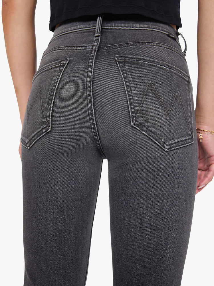 Close view of a woman in a faded black flare jean with a mid rise and 31-inch inseam and a clean hem. 