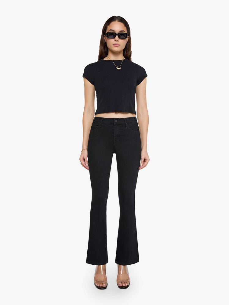Front view of a woman in a dark black flare jean with a mid rise and 31-inch inseam and a clean hem. 