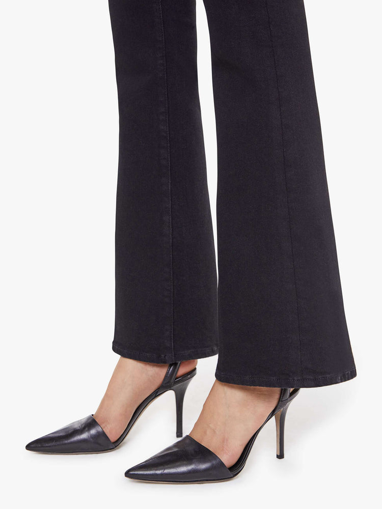 Hem view of a woman in a dark black flare jean with a mid rise and 31-inch inseam and a clean hem. 