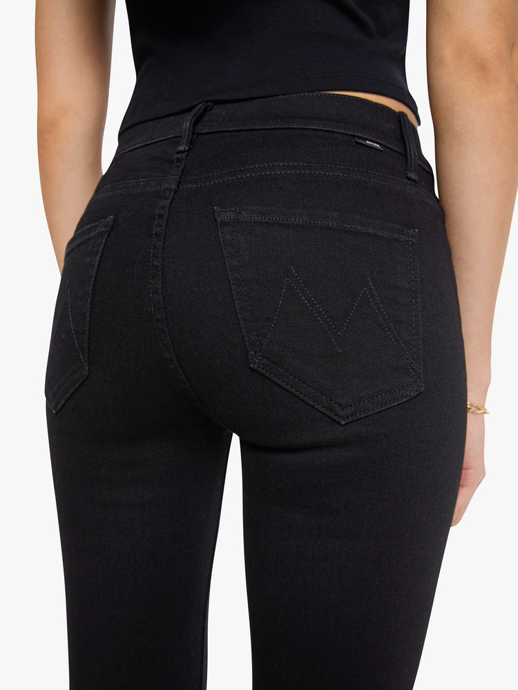 Close up view of a woman in a dark black flare jean with a mid rise and 31-inch inseam and a clean hem. 