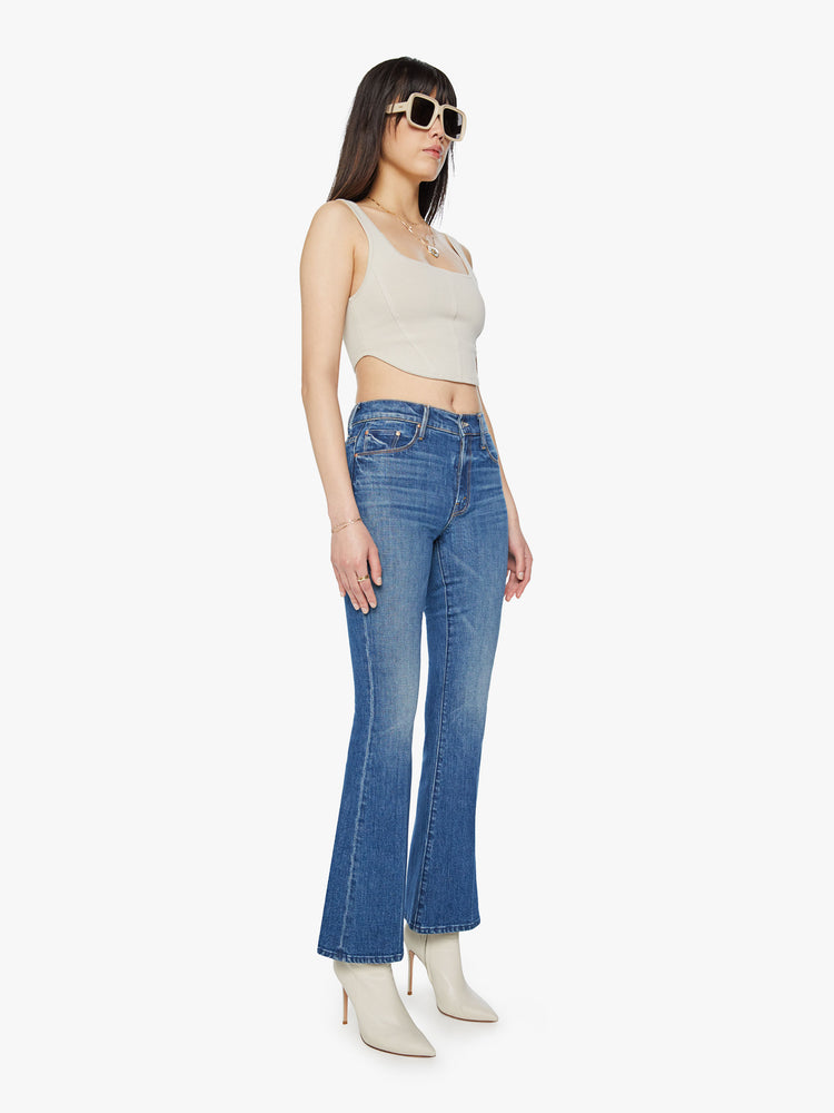 Side angle view of a mid rise blue flare jean with a 32 1/2-inch length inseam and a clean hem. 