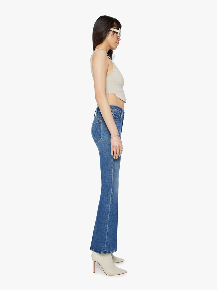 Side view of a mid rise blue flare jean with a 32 1/2-inch length inseam and a clean hem.