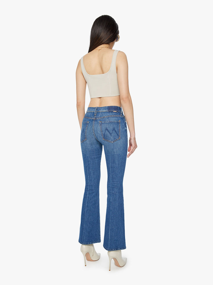 Back view of a mid rise blue flare jean with a 32 1/2-inch length inseam and a clean hem.