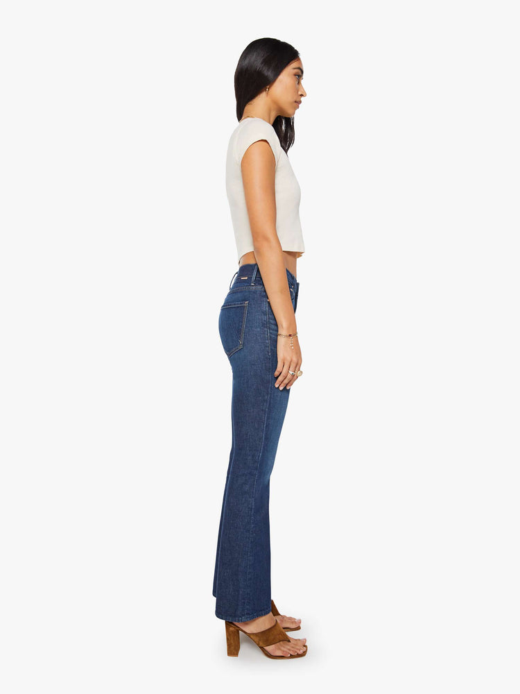 Side view of a dark blue mid rise jean with a 31-inch inseam and a clean hem.