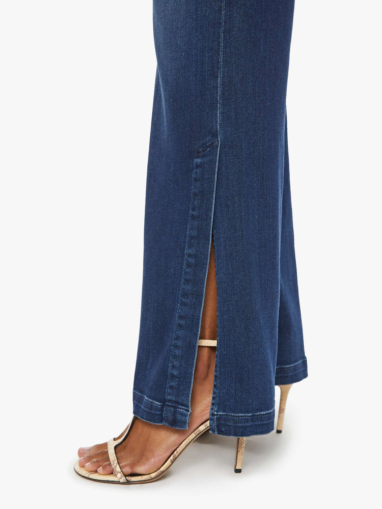 Hem close up view of a woman high-waisted wide-leg jeans with a long inseam and a thick side-slit hem in a dark blue wash.