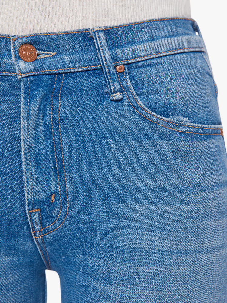 Swatch view of a woman mid blue wash mid-rise bootcut has an ankle-length inseam and raw hem.