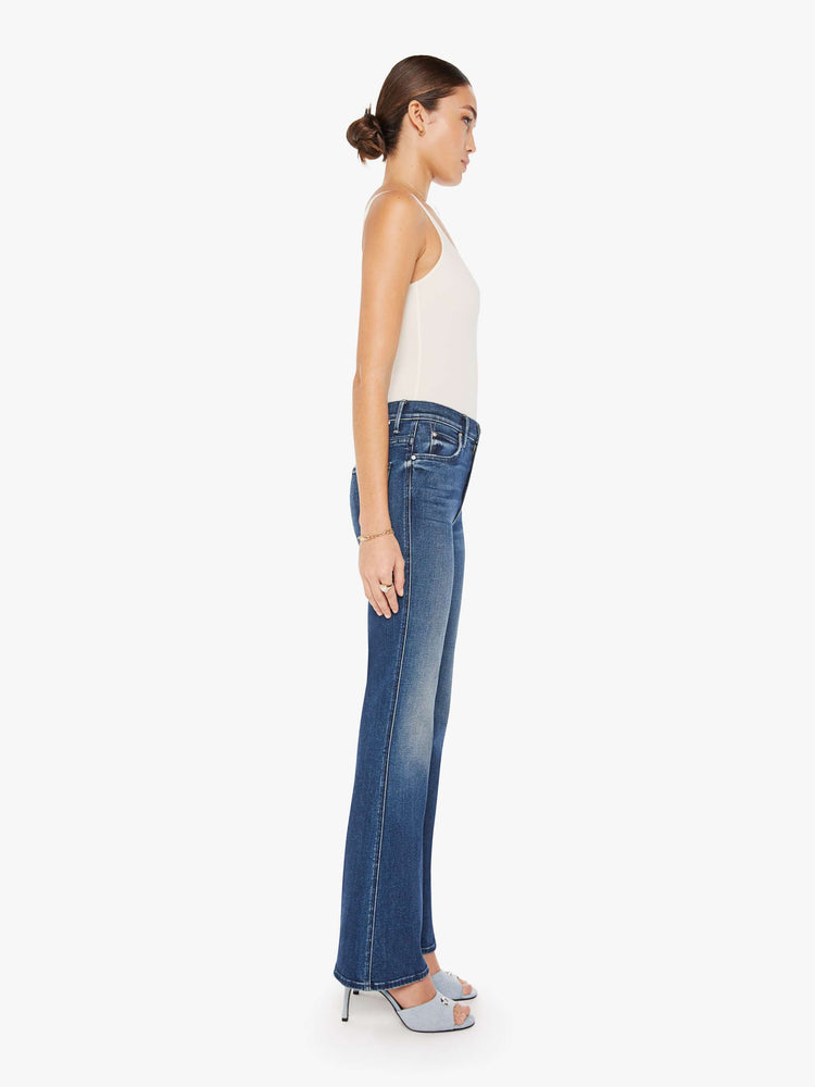 Side view of a womens dark blue wash jean featuring a high rise, flare, and full length clean hem.