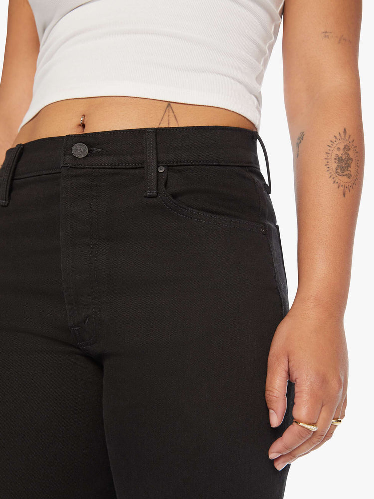 Close up view of a women's black straight leg jean with a high rise and ankle length inseam