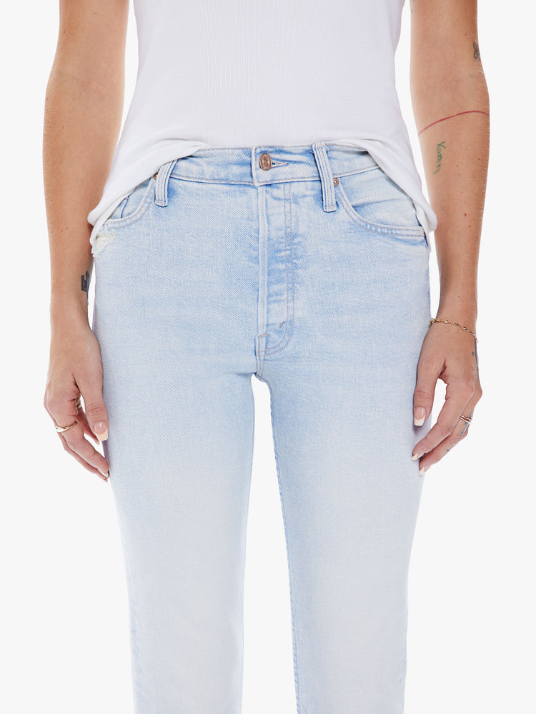 Close up waist view of a women high-rise jean with a straight leg, button fly, ankle-length inseam and a clean hem in a light blue hue.