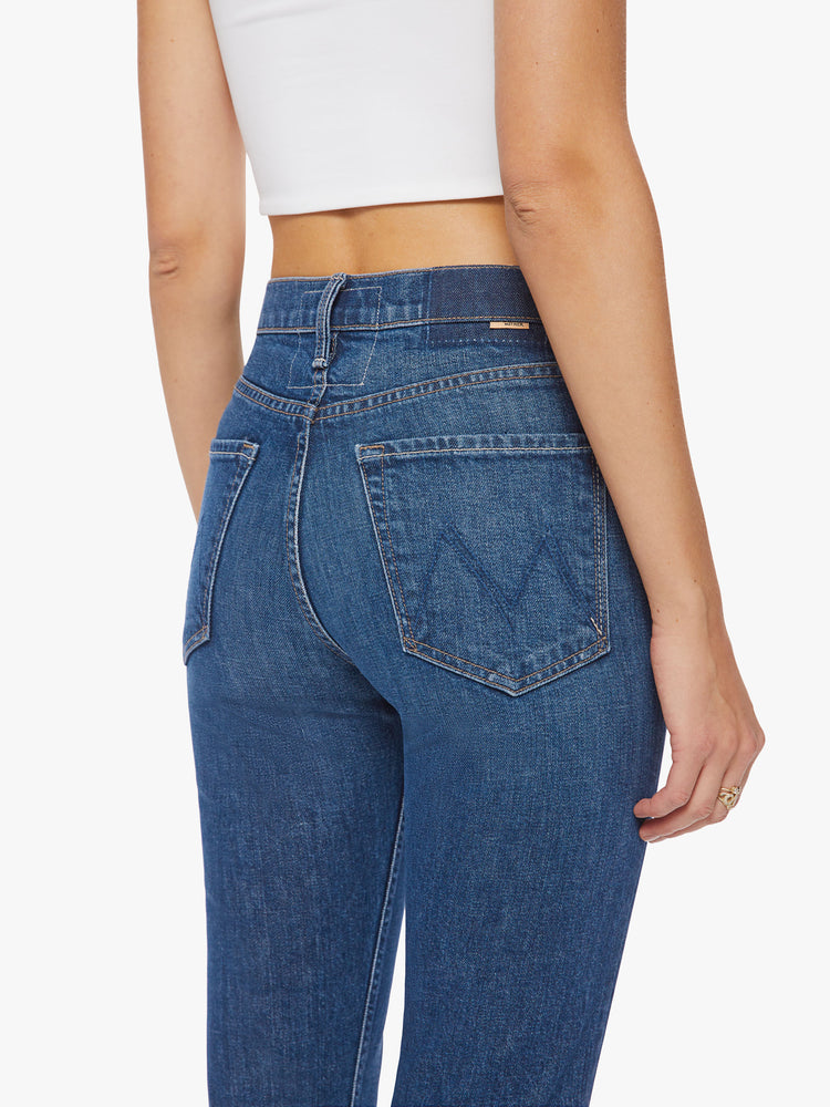 Close up back  view of a women's high-rise jean with a straight leg, button fly, ankle-length inseam and a clean hem in a dark blue wash.